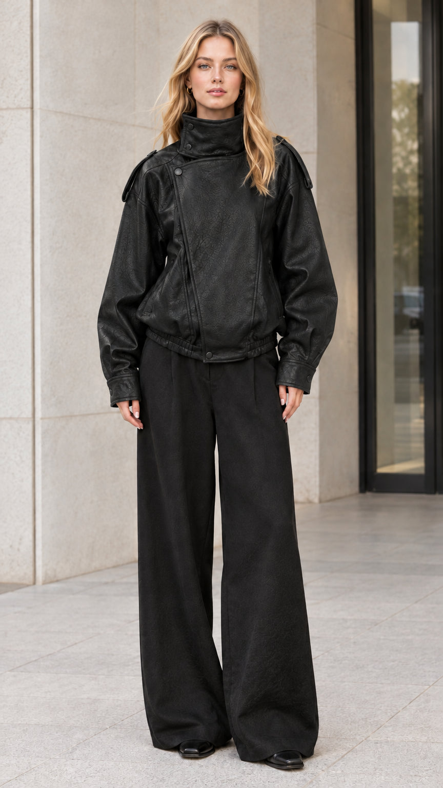 Front full-body view of model wearing black high-neck faux leather bomber jacket with black wide-leg pants