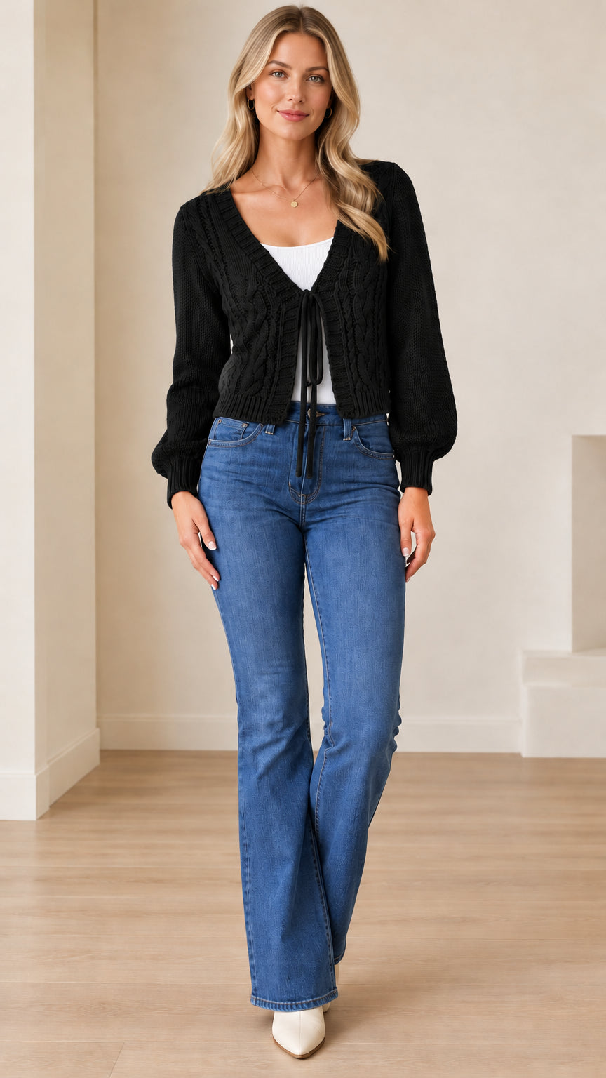 Full front view of a model wearing the black cable knit tie-front cropped cardigan with blue denim