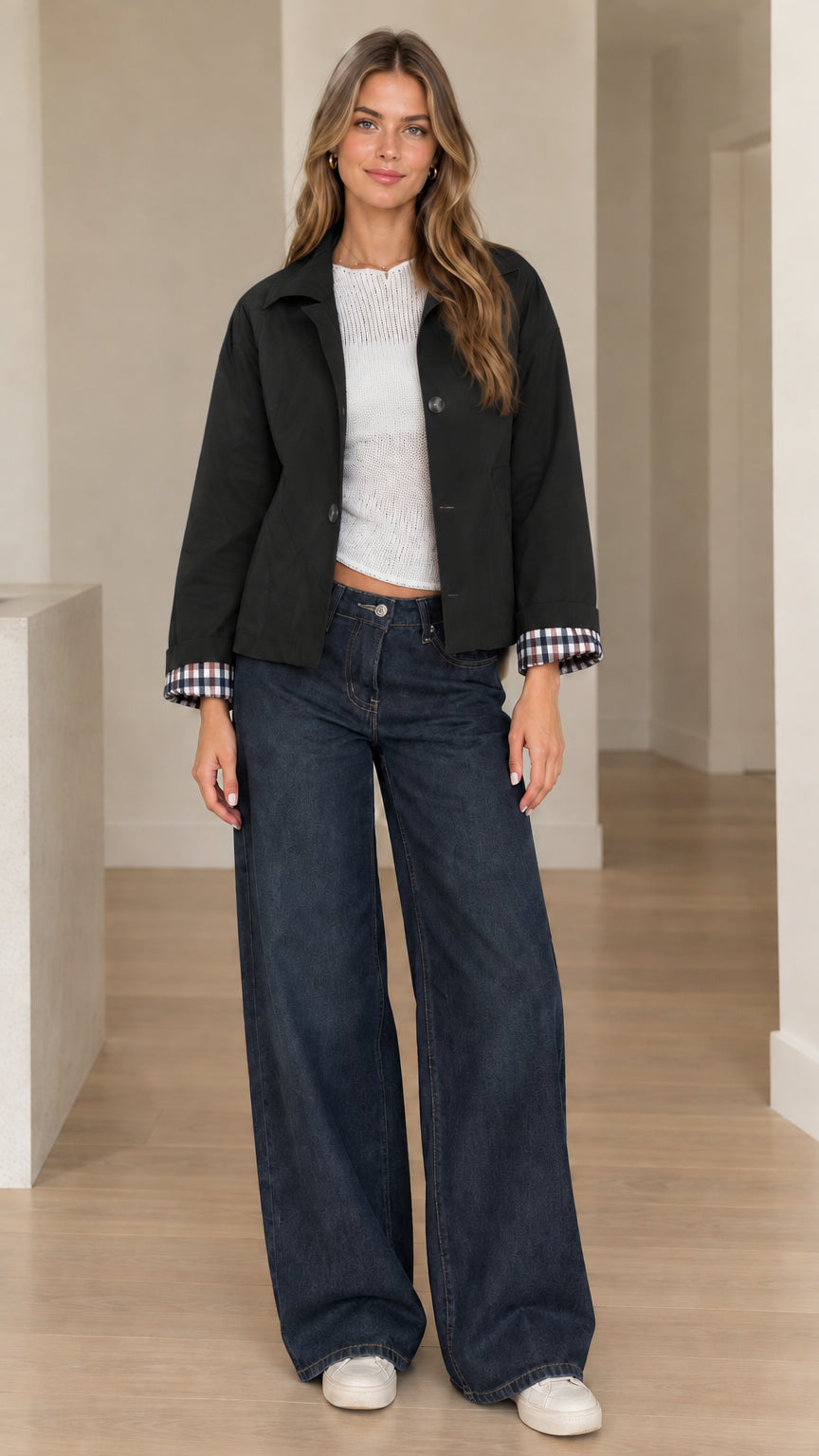 Front view of woman wearing black collared short jacket with rolled plaid cuffs