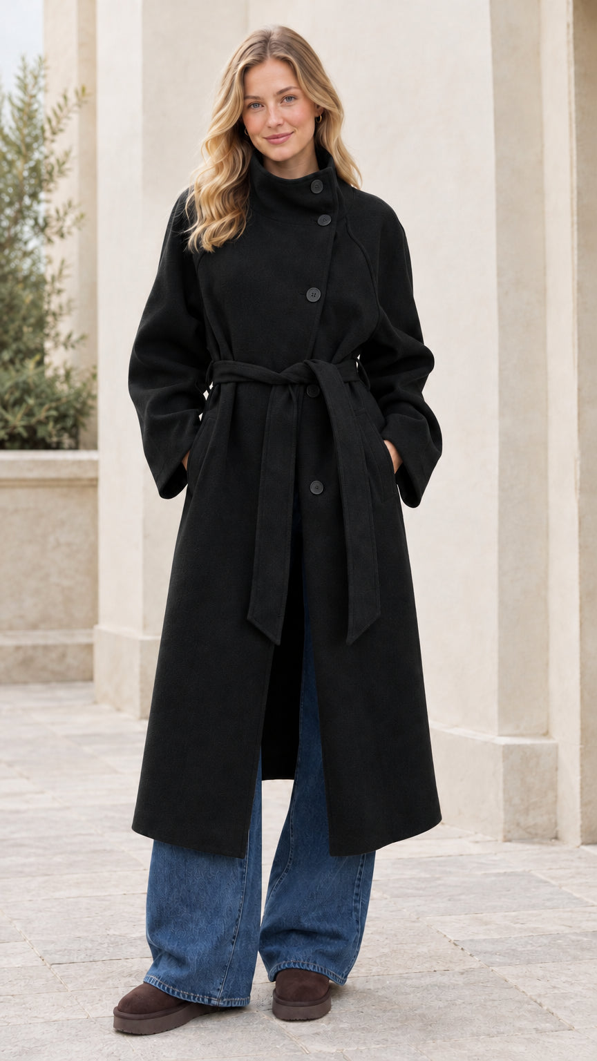 Front full view of woman wearing the black asymmetrical high-neck belted overcoat