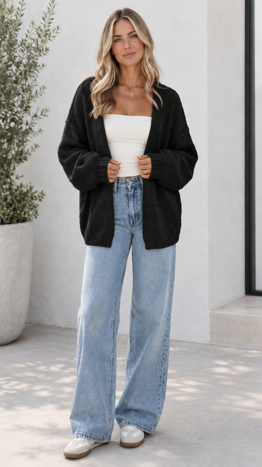 Model wearing black open front oversized knit cardigan with light blue jeans