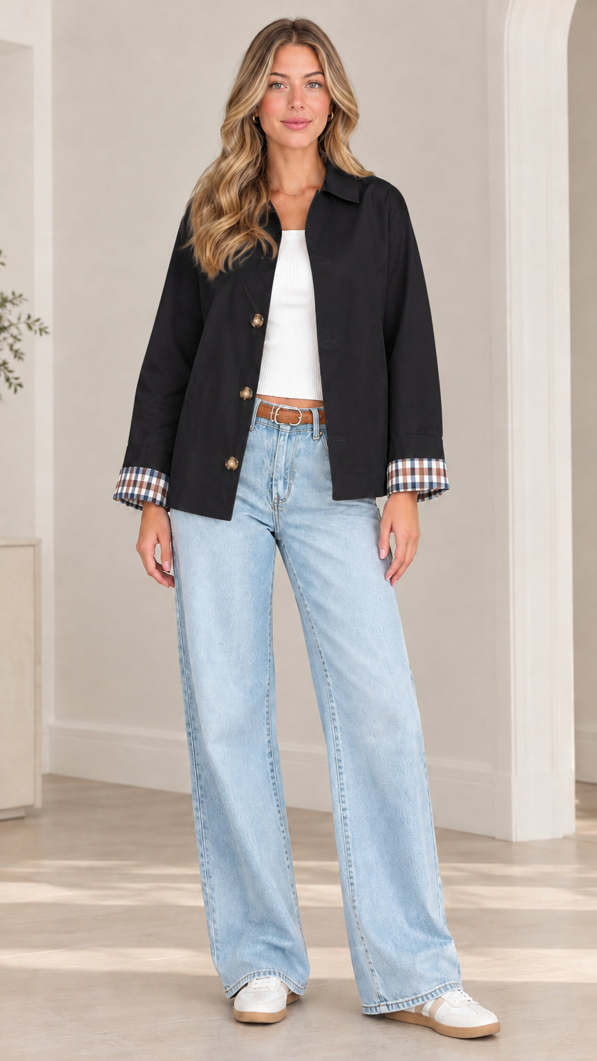 Front view of model wearing black button-front shirt jacket with turn-back plaid cuffs