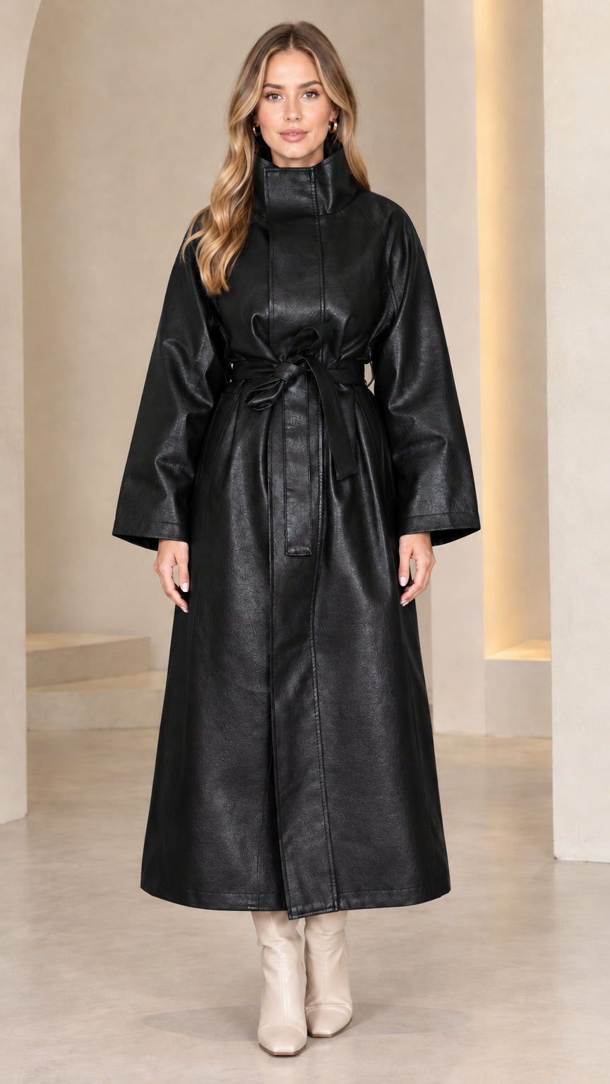 Front view of model wearing classic black high neck belted faux leather maxi coat