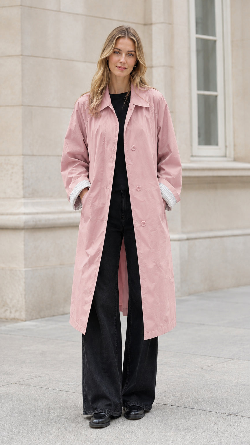 Front full-length view of model wearing a light pink long belted trench coat