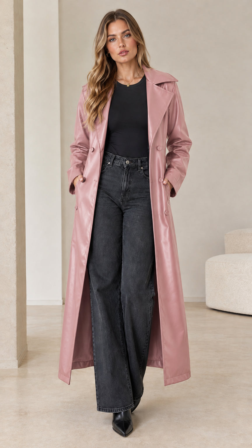 Front view of model wearing a dusty pink faux leather maxi trench coat over black top and wide leg jeans