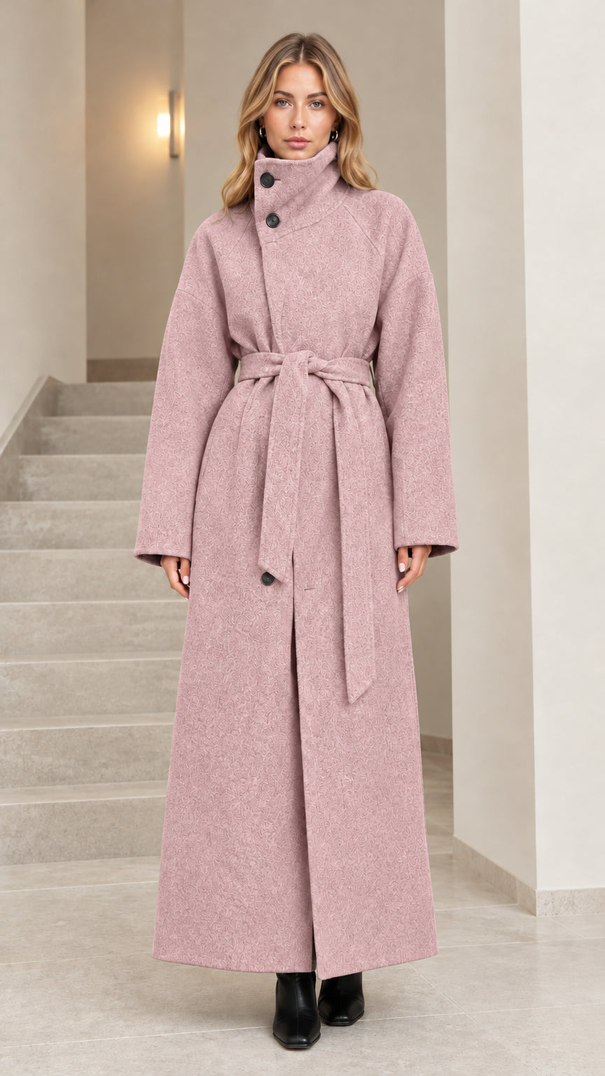 Front view of woman wearing dusty pink high collar belted maxi overcoat