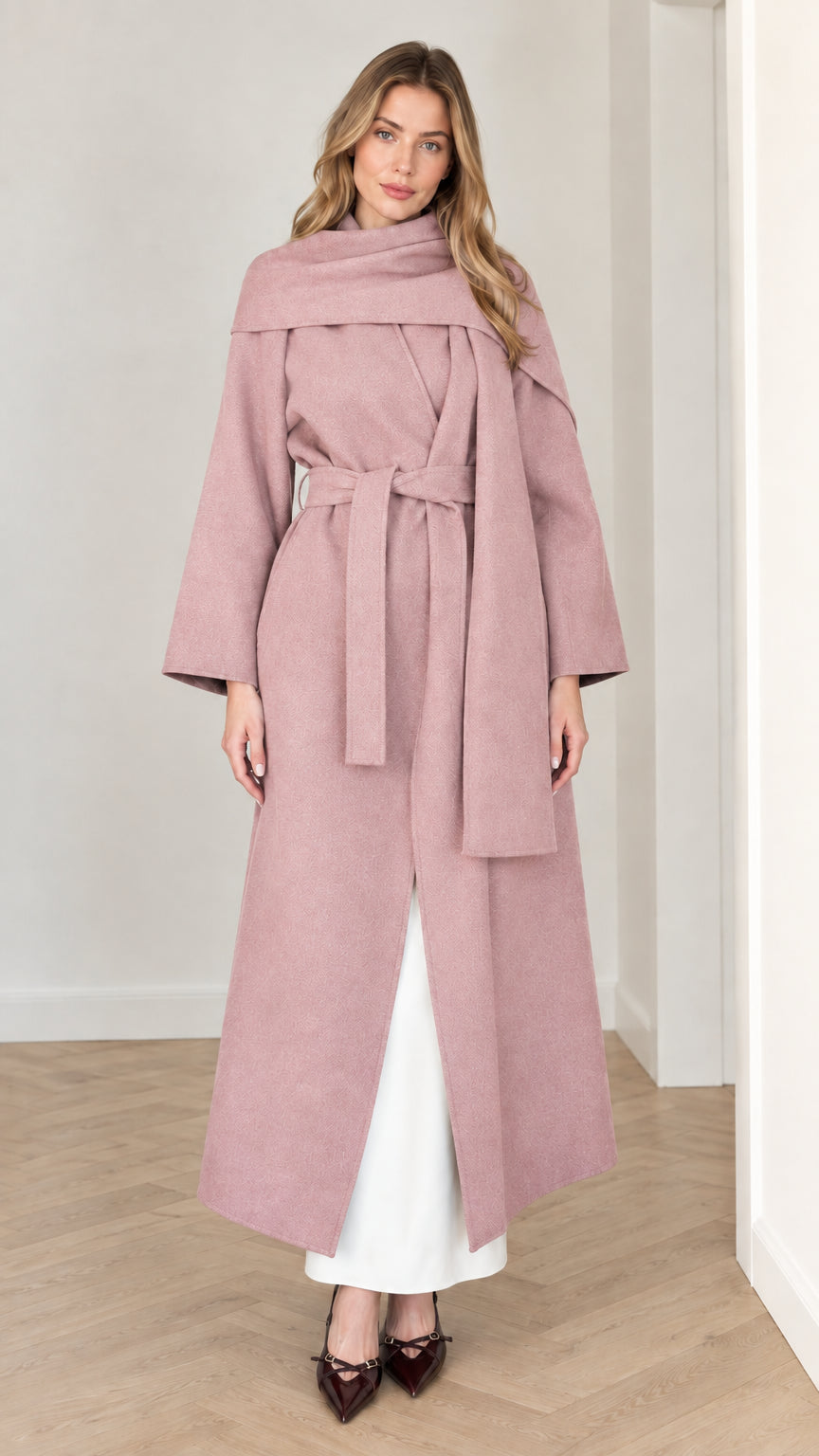 Model wearing dusty pink long belted wrap coat with integrated draped scarf