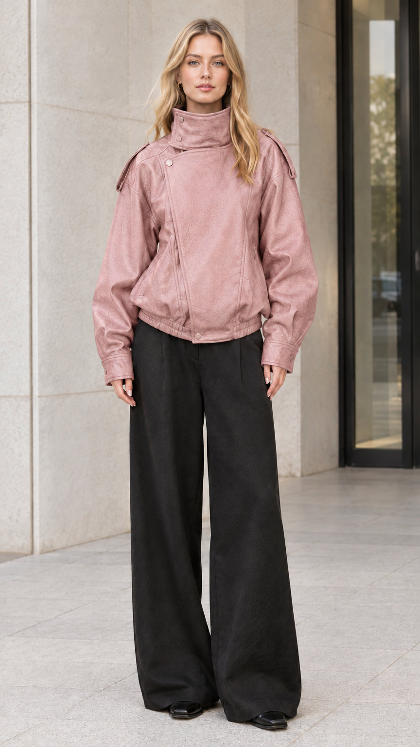 Front full-body view of model wearing dusty pink faux leather bomber jacket with black trousers