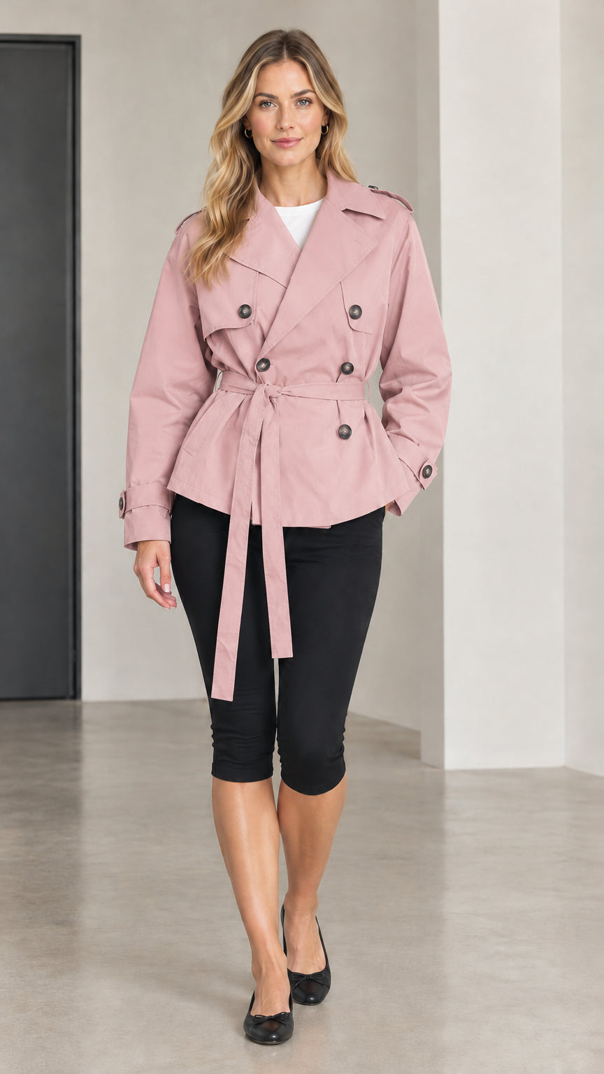Front view of woman wearing pink short double-breasted trench coat with tie belt