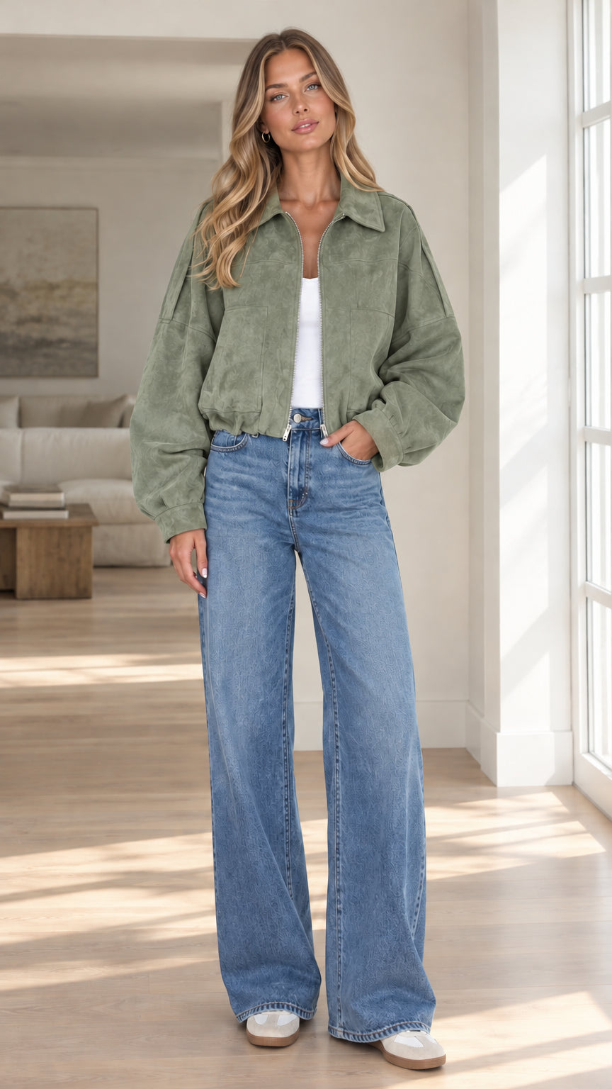 Front view of model wearing sage green cropped faux suede bomber jacket with denim pants