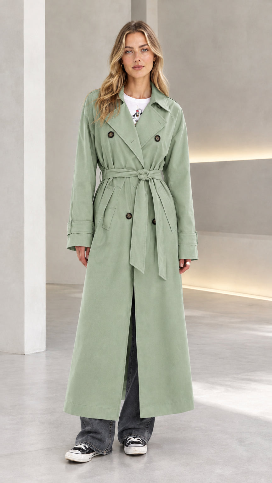 Front view of model wearing sage green double-breasted long belted trench coat
