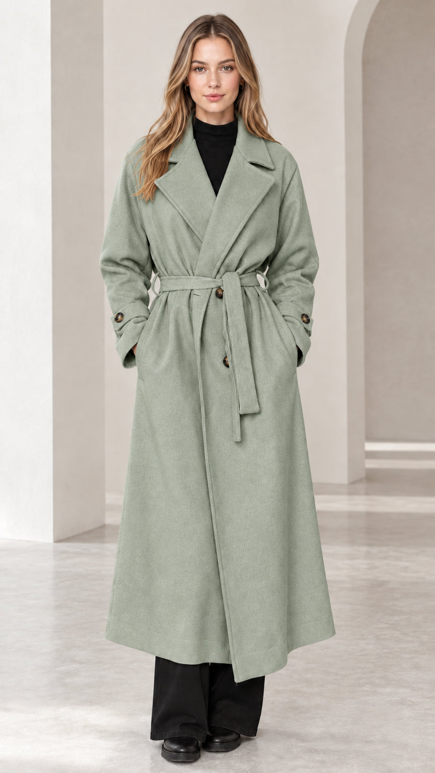 Front view of woman wearing sage green long belted trench overcoat