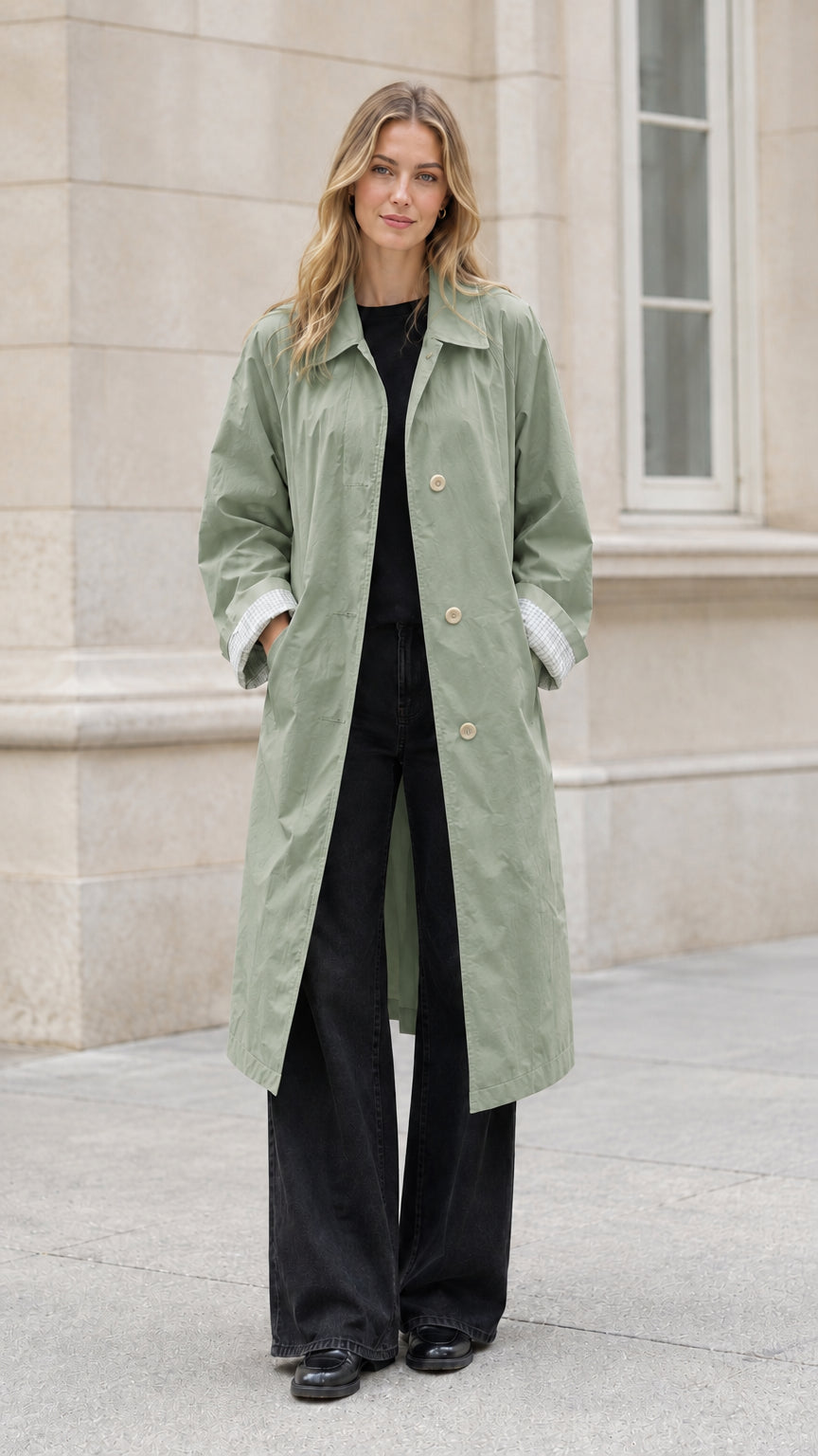 Front full-length view of model wearing a sage green long belted trench coat