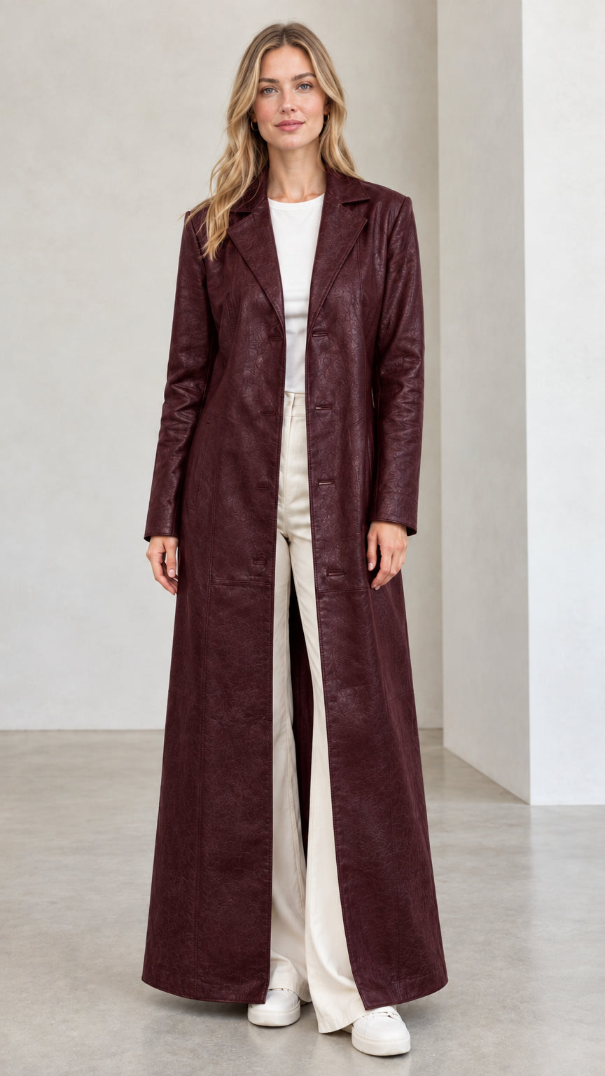 Front full view of woman wearing deep burgundy full-length faux leather trench coat