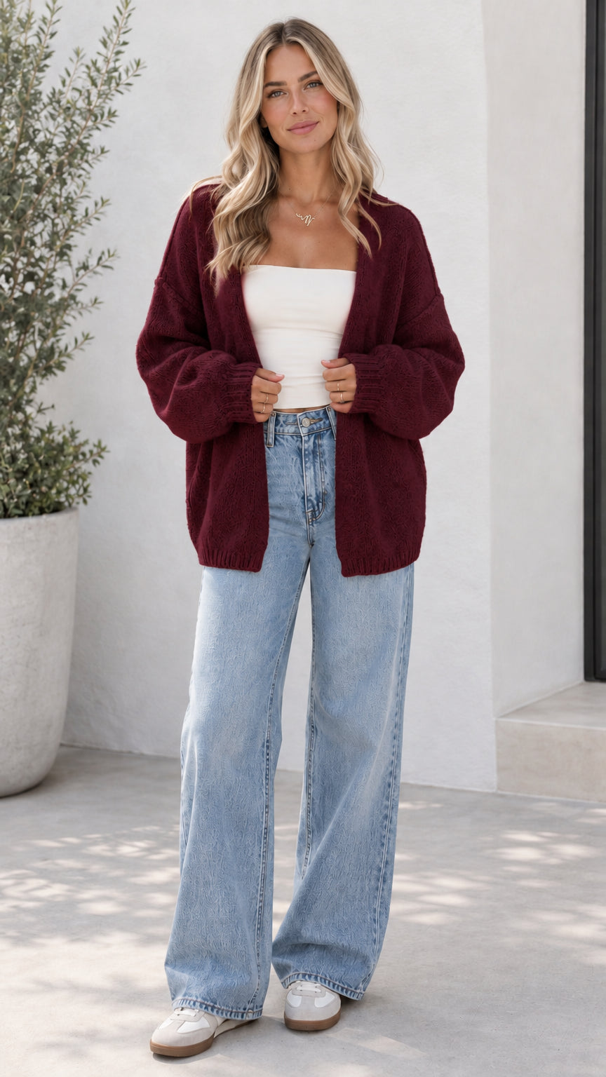 Model wearing burgundy open front oversized knit cardigan with light blue jeans