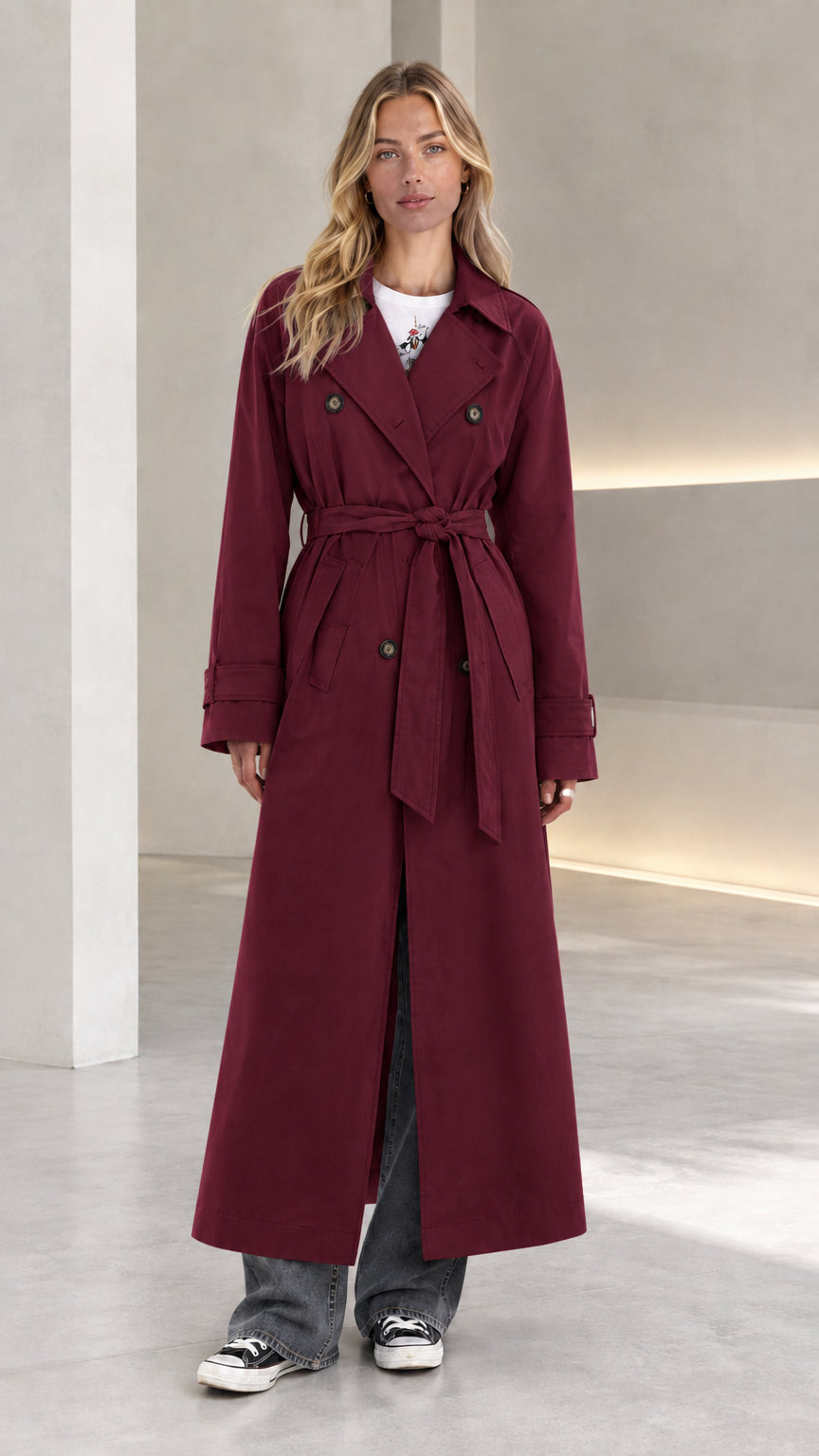 Front view of model wearing burgundy wine red double-breasted long belted trench coat