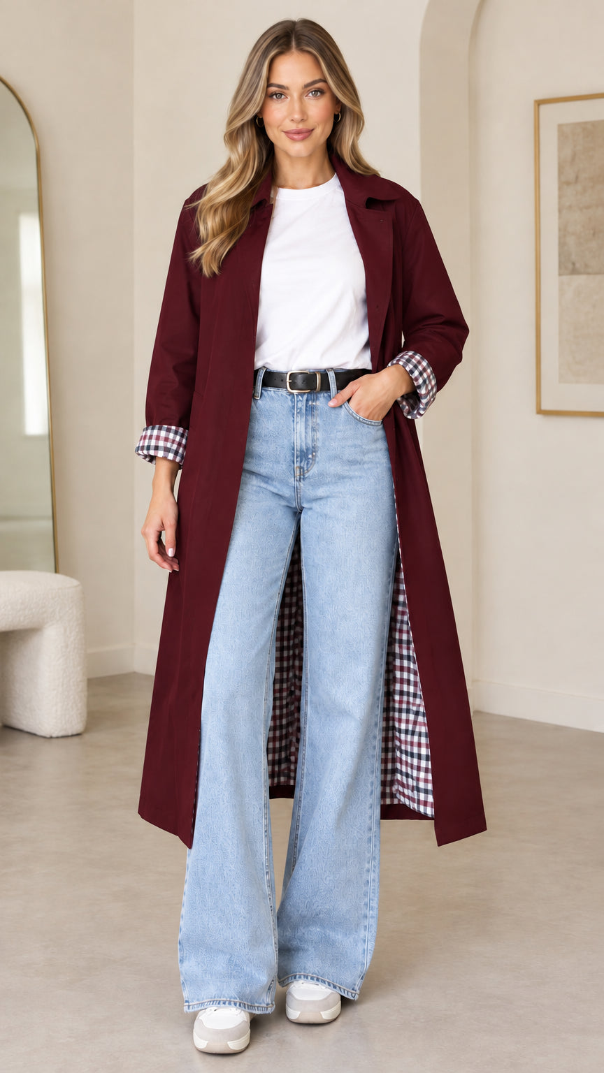 Front full-length view of woman wearing burgundy long duster trench coat with plaid cuffs