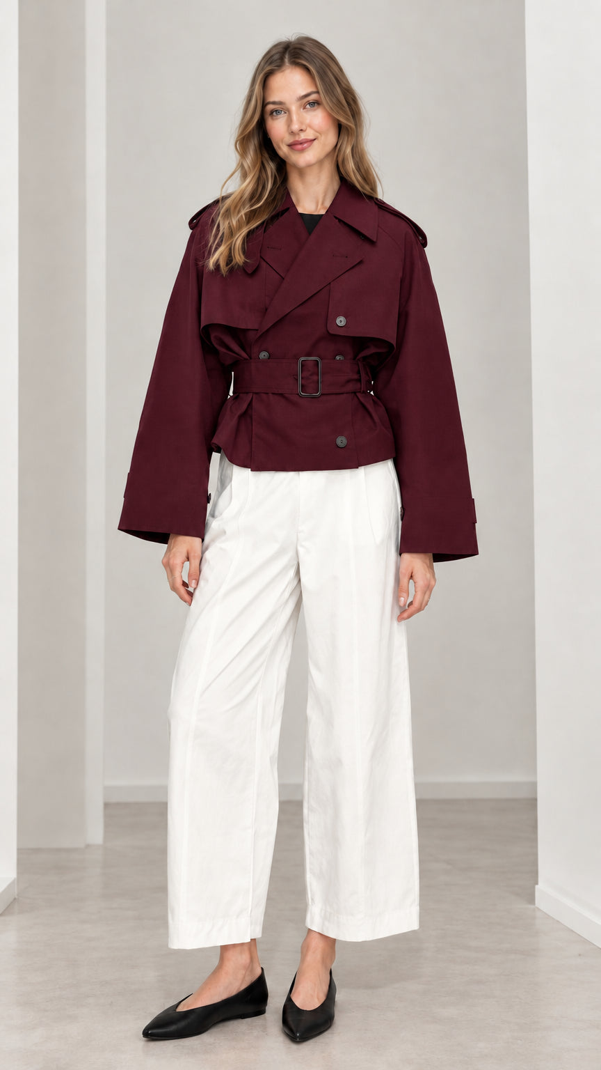 Front view of woman wearing burgundy wine red cropped double-breasted trench jacket with matching belt