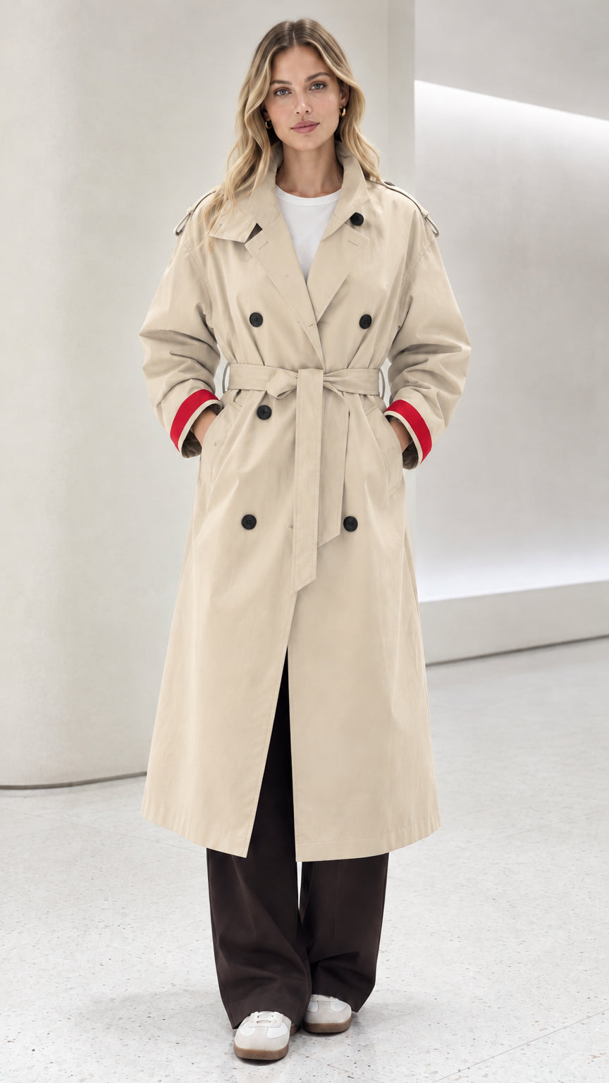 Front view of model wearing cream double-breasted trench coat with red contrast cuffs