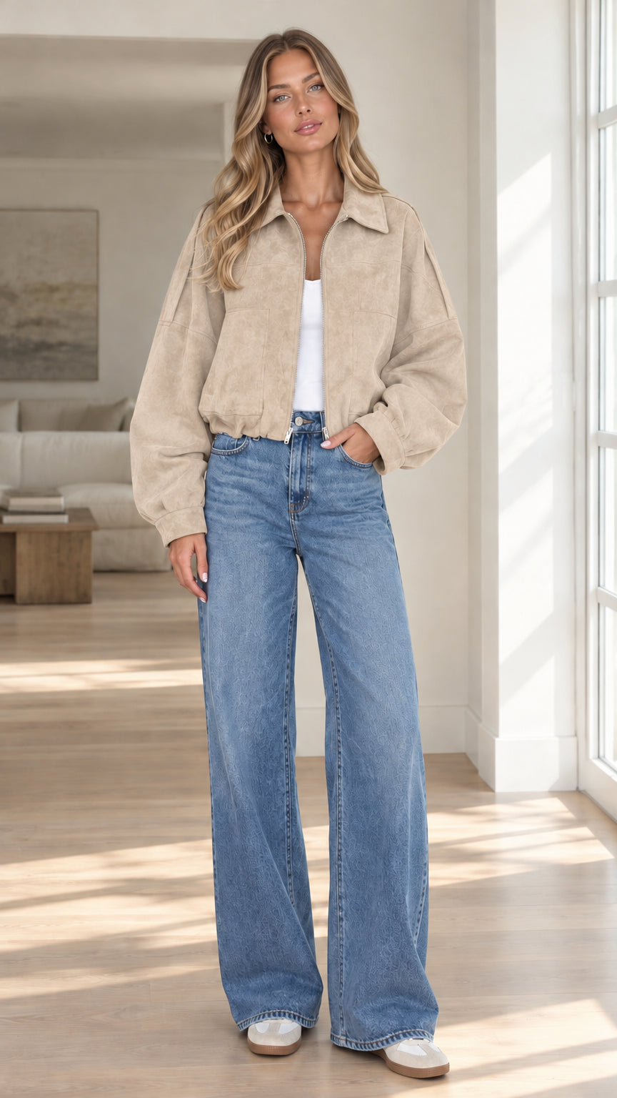 Front view of model wearing beige cropped faux suede bomber jacket with jeans