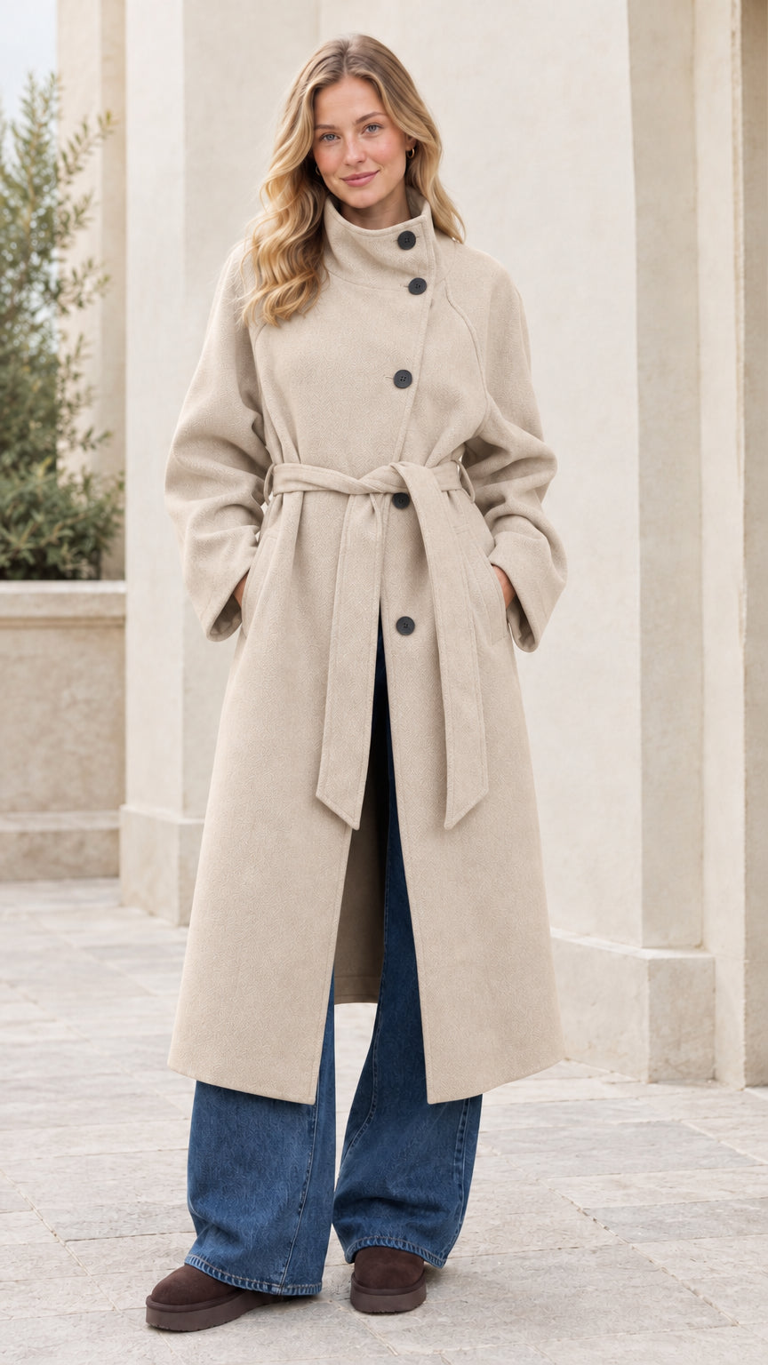 Front full view of woman wearing the beige cream asymmetrical high-neck belted overcoat