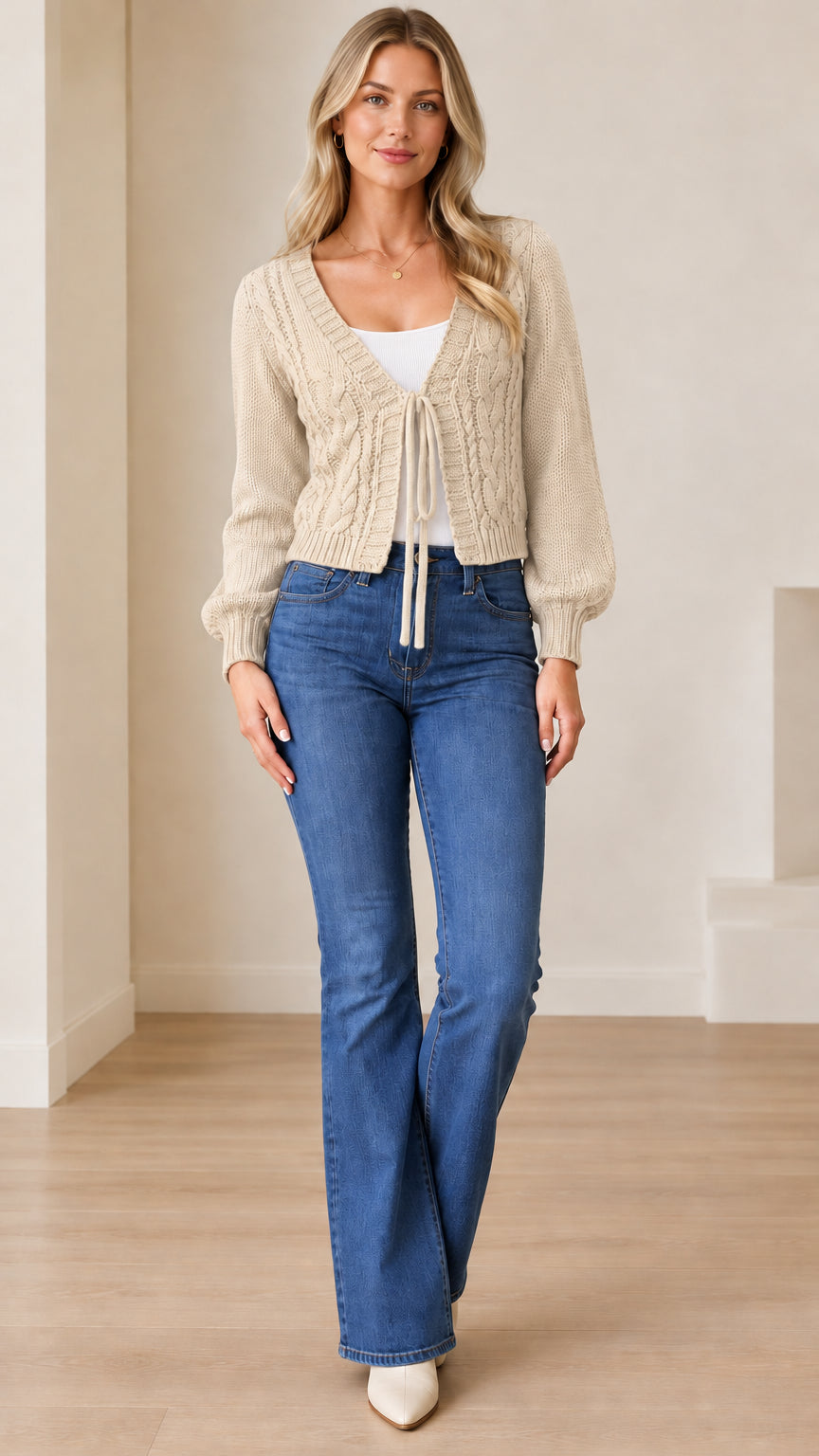 Full front view of a model wearing the beige cable knit tie-front cropped sweater with jeans