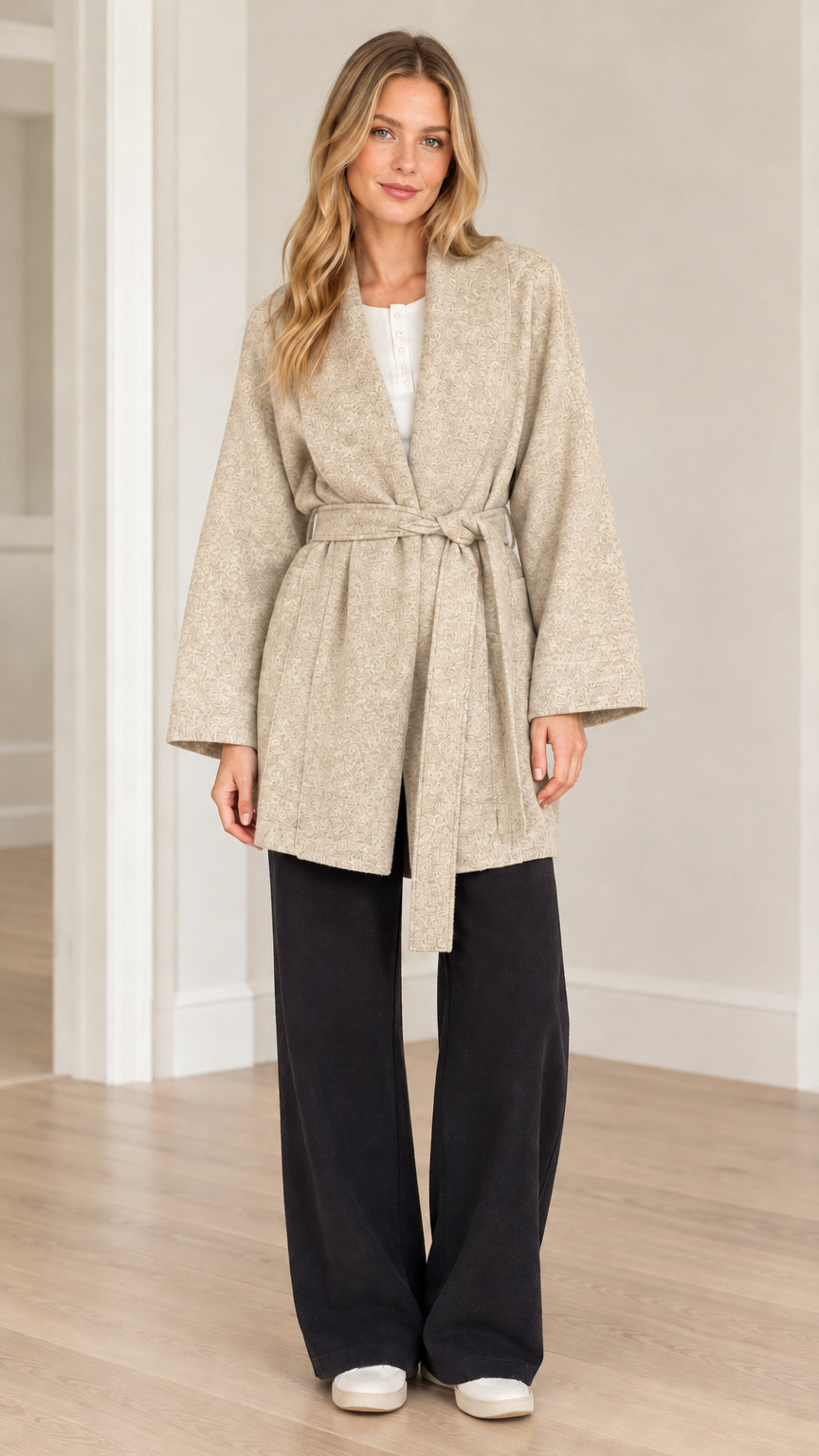 Front view of model wearing oatmeal beige textured herringbone belted wrap coat